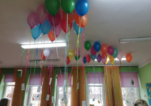 Balony wypełnione helem wiszą pod sufitem w sali przedszkolnej.